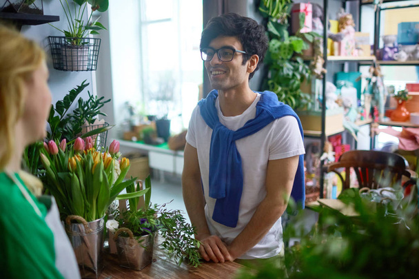 若い男のフラワー ショップで彼のガール フレンドのための花を買いに行く - 写真・画像