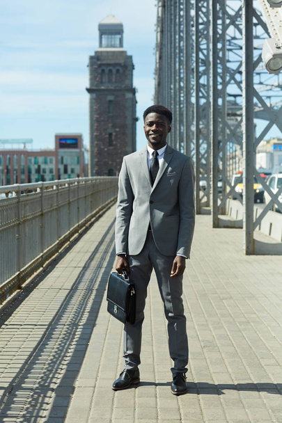 都市計画道路そばに立っているスーツのビジネスマン - 写真・画像