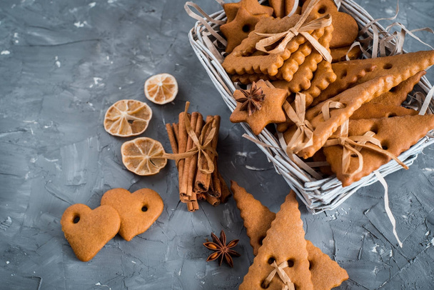 Christmas spices, gingerbread cookies and baking ingredients on grey concrete background. Cinnamon, anise stars, nutmeg, cardamon, cloves, brown sugar for Christmas cookies. - Foto, Imagem