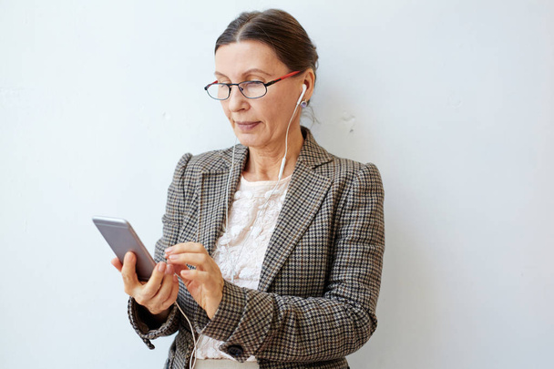 Contemporary businesswoman watching something online in her smartphone - Foto, imagen