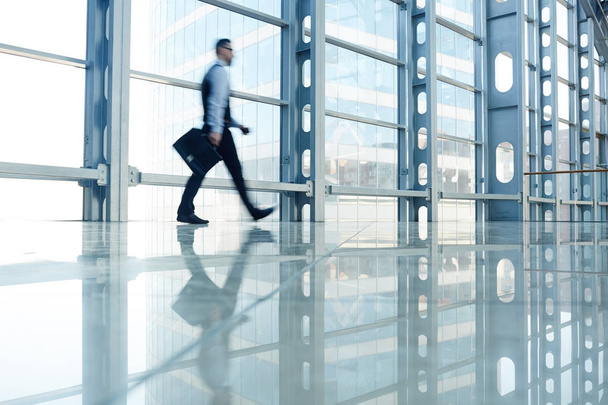Forme floue de l'homme d'affaires marchant dans le hall du bâtiment en verre moderne, allant au travail
 - Photo, image
