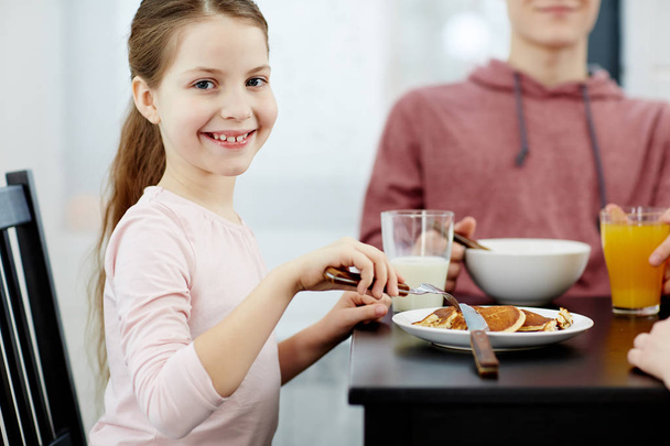 Smiley-Mädchen blickt beim Frühstück in die Kamera - Foto, Bild