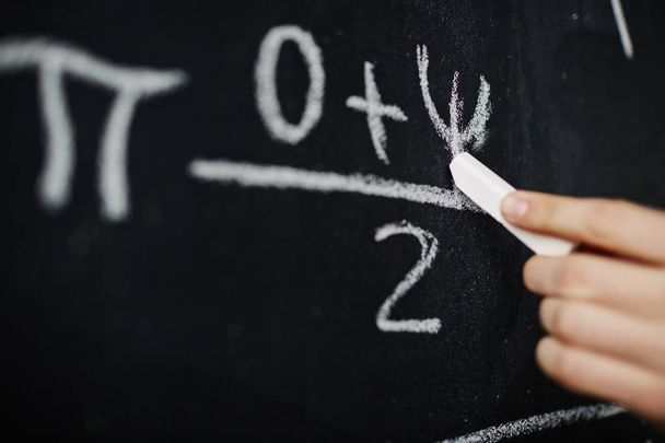 Closeup of hand writing mathematic formula on blackboard with chalk - Photo, Image