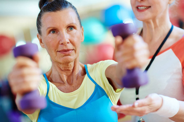 Warm-up of active senior woman in gym - Foto, imagen