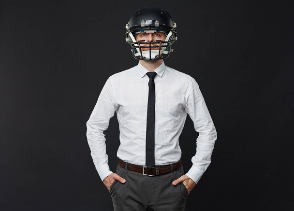 黒の背景にポケットに彼の手で立っている間アメリカン フットボール用ヘルメットを着用大人のビジネスマン半ば自信の肖像画 - 写真・画像