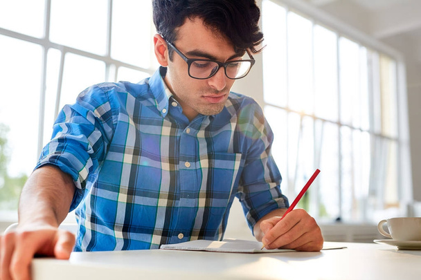 Estudiante moderno con dibujo a lápiz en copybook by desk
 - Foto, imagen