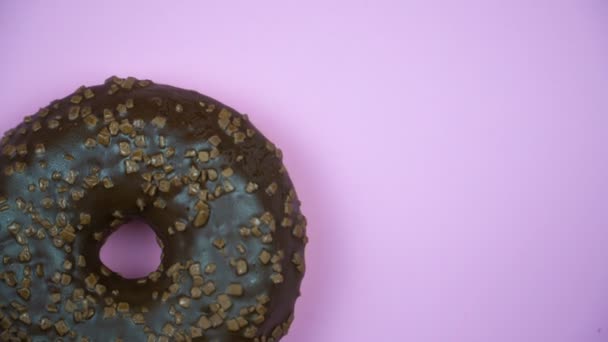 Heerlijke zoete donut draaien op een plaat. Bovenaanzicht. Helder en kleurrijk bestrooid donut close-up macro geschoten spinnen op een roze achtergrond. - Video
