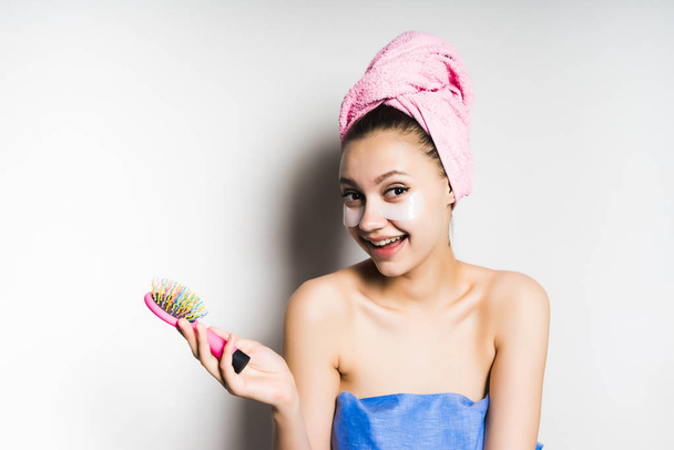 girl with a towel on her head smiling holding a comb in her hand - Фото, изображение