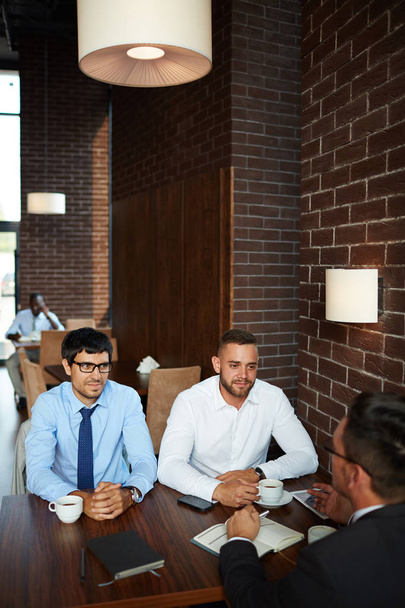 Бородатые бизнесмены проводят неформальную встречу в ресторане: они проводят мозговой штурм по совместному проекту, выпивая ароматный кофе
 - Фото, изображение