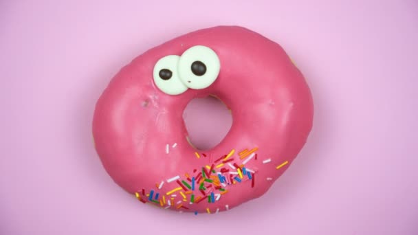 Délicieux donut sucré tournant sur une assiette. Vue de dessus. Lumineux et coloré saupoudré donut gros plan macro tournage sur un fond rose
. - Séquence, vidéo