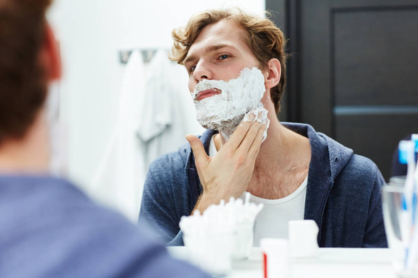 Jovem aplicando espuma de sabão ou creme de espuma antes da barba
 - Foto, Imagem