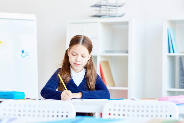 Inspired schoolgirl sketching in notebook at lesson - Фото, зображення