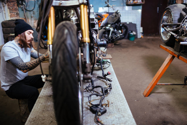 Портрет человека с татуировкой с боковым видом на ремонт и настройку мотоциклов
 - Фото, изображение