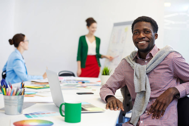 Счастливый студент или дизайнер сидит за столом в рабочей среде
 - Фото, изображение
