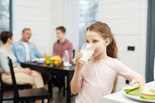 Menina saudável beber leite de vidro na cozinha
 - Foto, Imagem