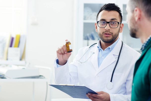 予定の中に彼の患者にボトルで新しい薬を説明するホワイト コートの専門医 - 写真・画像