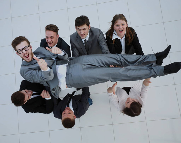 Business team happily throws up their colleague in the air celeb - Fotó, kép