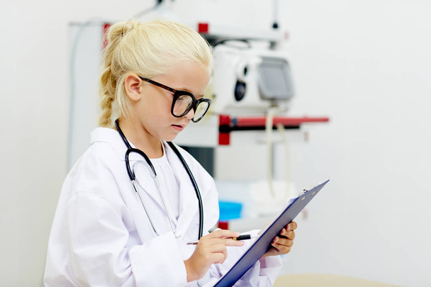 Little clinician making notes in medical document during work - Photo, Image