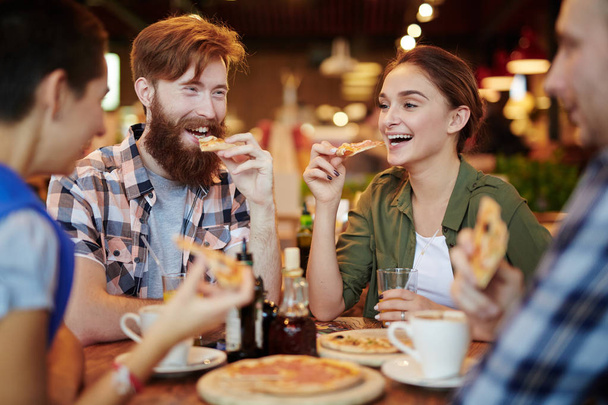 Joyful friends gathered together in pizza restaurant and chatting animatedly with each other, waist-up portrait - Fotoğraf, Görsel