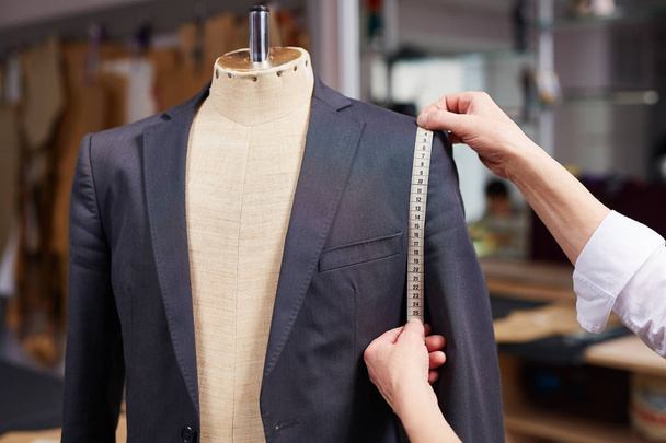 Closeup of tailors hands measuring jacket with tape fitting bespoke suit - Foto, Imagen