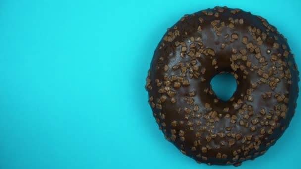 Heerlijke zoete donut draaien op een plaat. Bovenaanzicht. Helder en kleurrijk bestrooid donut close-up macro geschoten spinnen op een blauwe achtergrond. - Video