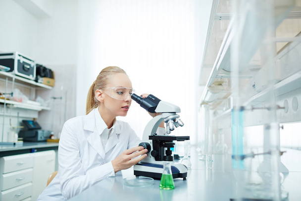 Πορτρέτο του όμορφη ξανθιά επιστήμονας χρησιμοποιώντας μικροσκόπιο που εργάζονται για την ιατρική έρευνα στο σύγχρονο εργαστήριο - Φωτογραφία, εικόνα