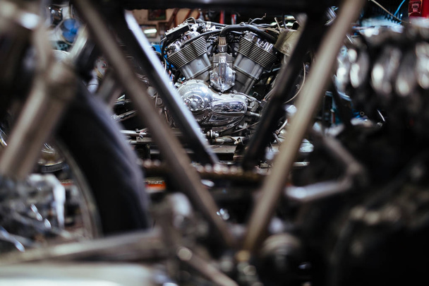 Mehrere in einer Garage hintereinander stehende Motorräder bilden einen abstrakten Hintergrund aus Metallteilen - Foto, Bild