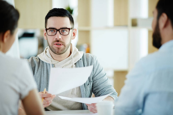 Portrait of  adult man dressed in business casual discussing work with colleagues at meeting table in modern office - Foto, afbeelding