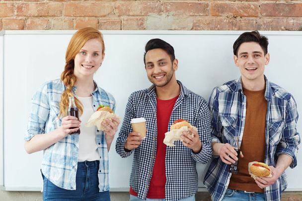 ハンバーガーと飲み物で空腹の学生のグループ - 写真・画像