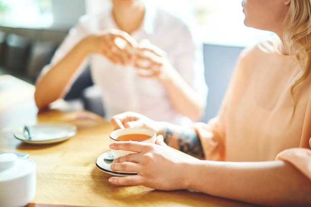 Jovens meninas amigáveis tomar chá e conversar na cafetaria no fim de semana
 - Foto, Imagem