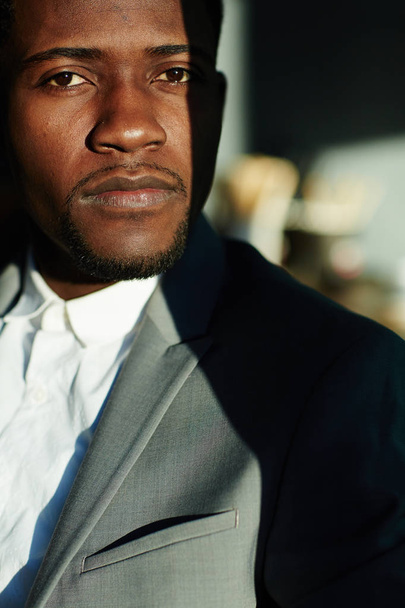 Parlak gün ışığı altında duran ve ciddi bir ifadeyle kameraya bakarak yakışıklı Afrikalı-Amerikalı adam portresi iş - Fotoğraf, Görsel