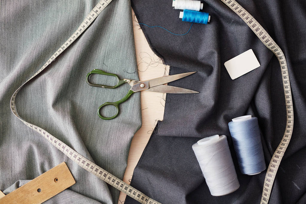 Lähikuva kuva eri ompelu kohteita pöydällä: sakset, mittanauha ja ompelu puolat
 - Valokuva, kuva