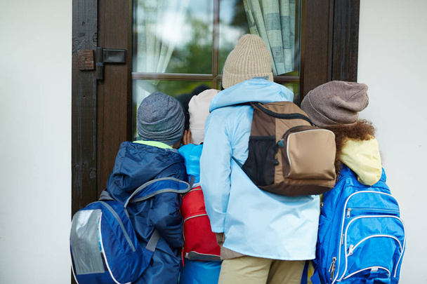 Meraklı schoolkids ile okul kapıdan seyir turistik arka çantalar - Fotoğraf, Görsel