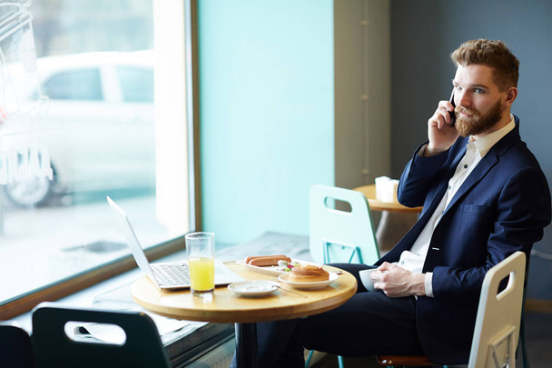 Calling man in suit having meals and tea in cafeteria - Photo, image