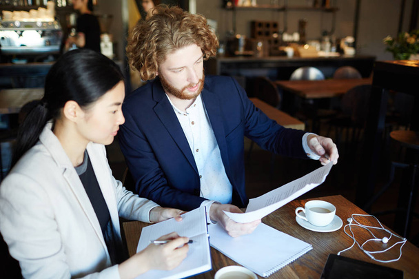 Молодые коллеги по бизнесу обсуждают документы в кафе на встрече
 - Фото, изображение