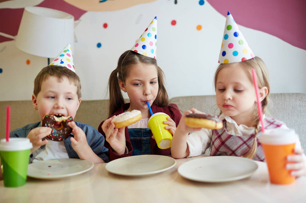 Grupo de crianças famintas comendo donuts com refrigerante
 - Foto, Imagem
