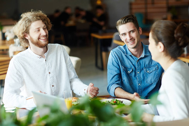 Nauravat kaverit puhuvat ystävälleen tai kollegalleen lounaalla kahvilassa
 - Valokuva, kuva