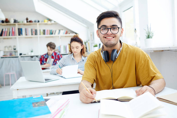 Happy guy with headphones preparing homework - Foto, imagen