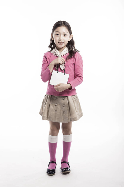 Азиатская (корейская, японская, китайская) девушка (ребенок, студентка, ребенок, женщина, женщина) в розовой блузке держит и смотреть (см.) пустой (пустой, пустой, полый) торговый пакет (бумажный пакет) изолированы белый
. - Фото, изображение