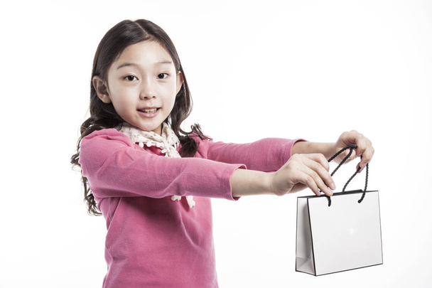 Dziewczyna Azji (korea, japoński, chiński), (dziecko, uczeń, dziecko, Kobieta, samica) sobie trzymać różowa bluzka i watch(see) pusty (puste, niezabudowana, puste) shopping bag (filtr workowy) na białym tle biały. - Zdjęcie, obraz