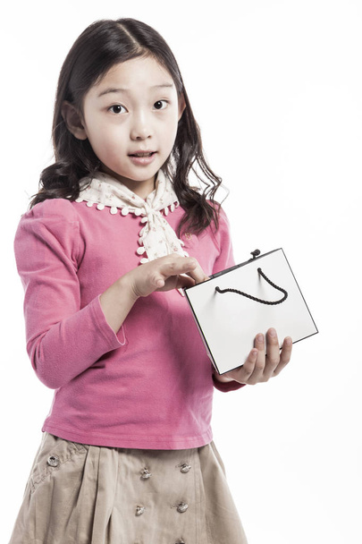 Азиатская (корейская, японская, китайская) девушка (ребенок, студентка, ребенок, женщина, женщина) в розовой блузке держит и смотреть (см.) пустой (пустой, пустой, полый) торговый пакет (бумажный пакет) изолированы белый
. - Фото, изображение