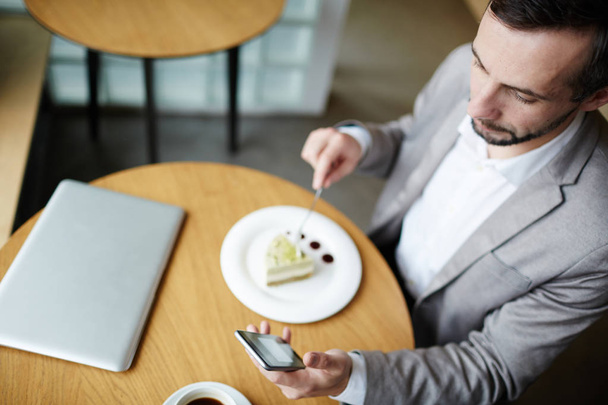 Homme d'affaires mobile textos tout en ayant dessert dans le café
 - Photo, image