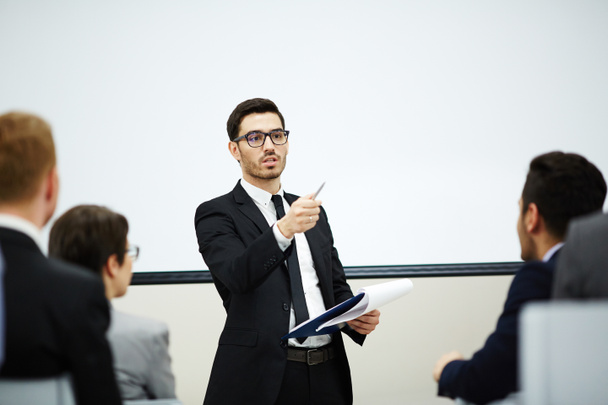 Entrenador de confianza señalando a uno de los oyentes mientras hace informe en el entrenamiento
 - Foto, imagen