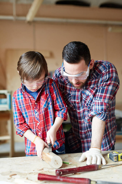 Woodcrafting malý chlapec a jeho otec mu poradenství - Fotografie, Obrázek