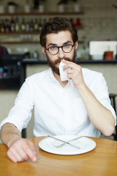 Geschäftsmann wischt sich nach Essen im Café mit Papierserviette den Mund ab - Foto, Bild
