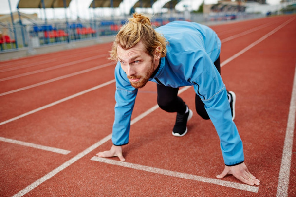Odhodlaný mladík v čekání na start signál během běhu soutěže sportovní oblečení - Fotografie, Obrázek
