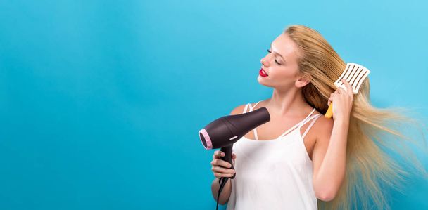 Beautiful woman holding a hairdryer - Photo, image