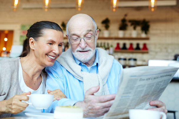 Mature man showing his wife latest news by cup of tea - Foto, immagini