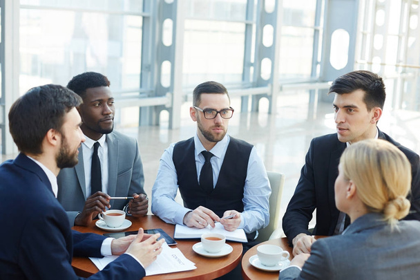Группа современных бизнесменов встречается в офисном здании и обсуждает работу
 - Фото, изображение