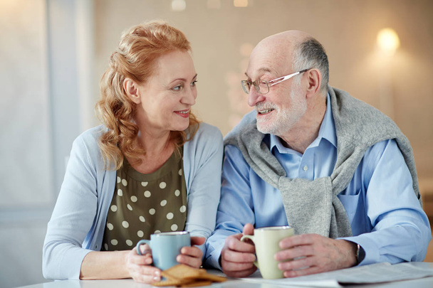 Cheerful and amorous mature man and woman having talk by tea - Photo, Image
